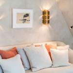 Ein Sofa mit Kissen unter zwei Wandlampen und einem Bild an der Wand.