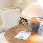 Runder Tisch mit Lampe und Buch neben einem Sessel.