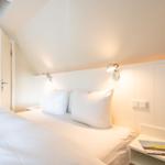 Schlafzimmer mit Doppelbett, Nachttisch und angrenzender Toilette.