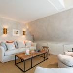 Wohnzimmer mit Sofa, Sessel und Holztisch unter Dachschrägen.