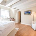 Schlafzimmer mit Dachschräge, weißem Bett und Holzboden.