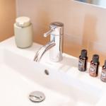 Waschbecken mit Wasserhahn und drei kleinen Fläschchen.