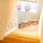 Holzstufen führen nach oben. Fenster mit zwei weißen Laterne.