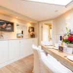 Esszimmer mit Holztisch, weißen Stühlen und dekorativen Elementen an der Wand.