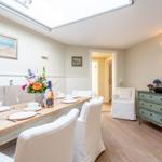 Esszimmer mit Tisch, Stühlen und Deckenfenster. Hintergrund: Flur und Schrank.