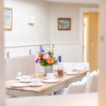 Esstisch mit Platz für sechs Personen, Blumen und Flasche auf dem Tisch.