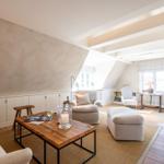 Dachgeschosswohnung mit Sitzgruppe, Tisch und Fenstern.