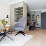 Wohnbereich mit Sofa, Sessel und Esstisch. Kaminofen und Holzfußboden sichtbar.