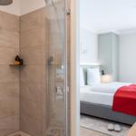 Dusche mit Glaswand und Badewanne im Hintergrund