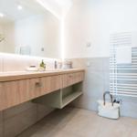 Badezimmer mit Holzwaschtisch, Spiegel und Handtuchhalter