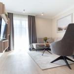 Wohnzimmer mit Sofa, Sessel und Fernseher an Wand