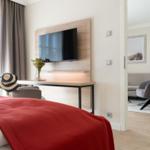 Schlafzimmer mit Bett, TV und Sicht in Wohnzimmer mit Sessel.
