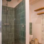 Bad mit Dusche, Toilette und Heizkörper an der Wand.
