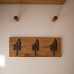 Holzpaneel mit drei Segelyachten-Haken an der Wand