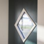 Schwarze Tür mit weiß gerahmtem Diamantfenster. Blick auf Außenbereich.