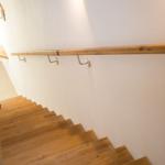 Holzgetäfelte Treppe mit Handlauf und Wandlampe.