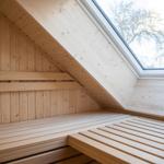 Holzsauna mit Dachschrägen und Fensterblick auf Bäume