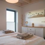 Zwei Betten mit Handtüchern, Schrank, Fenster und Wandbild.