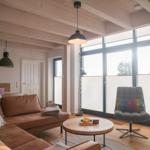 Wohnzimmer mit braunem Sofa, runden Tisch und großem Fenster.