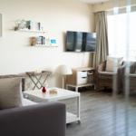 Wohnzimmer mit Sofa, Fernseher und Sitzgelegenheiten an der Glasfront.