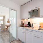 Küche mit Arbeitsplatte, Spüle und Glaswand zur Essnische.