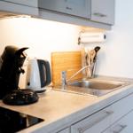 Küche mit Spüle, Kaffeemaschine und Wasserkocher.