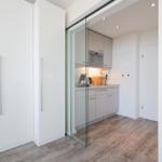 Küche mit Glaswand und weißen Schränken. Holzfußboden und integrierte Geräte.