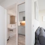 Wohnzimmer mit Sofa, Küche und Bad im Hintergrund.