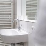 Bad mit Waschbecken, Spiegel und Heizkörper.