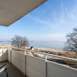 Balkon mit Sitzgelegenheit und Blick auf Strand und Meer.