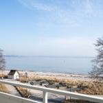 Blick auf Strand und See mit kleinem Haus und Bäumen