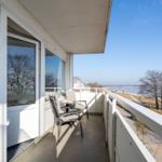 Terrasse mit Sitzgelegenheit und Blick auf Wasser und Strand.