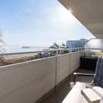 Balkon mit Sitzgelegenheit und Meerblick auf Pier und Strand.