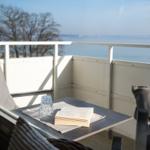 Balcony with table, book, and glasses overlooking the sea.