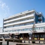 Moderne mehrstöckige Wohnanlage mit Balkonen und Geschäften im Erdgeschoss.