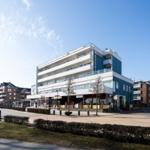 Moderne mehrstöckige Wohnanlage mit Balkonen und Geschäften im Erdgeschoss.