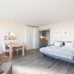 Wohnraum mit Schlafgelegenheit, Esstisch und Küchenbereich.