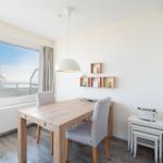 Esszimmer mit Tisch, Stühlen und Fensterblick auf Balkon