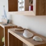 Holzregale mit Muscheln und Dekorationsgegenständen an der Wand