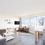 Wohn- und Essbereich mit Blick aufs Wasser und Bäume.