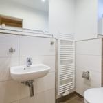 Badezimmer mit Waschbecken, Spiegel, Heizkörper und Toilette.