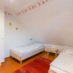 Zimmer mit zwei Betten, rotem Teppich und Wanddekoration mit Segelbooten.