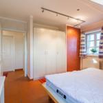 Schlafzimmer mit Bett, Kleiderschrank und Fenster mit Vorhängen.