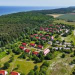 Liegenschaft mit roten Dächern, umgeben von Wald und Feldern, nahe dem Meer.