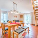 Esszimmer mit Holztisch, Stühlen und Treppe zur oberen Etage.