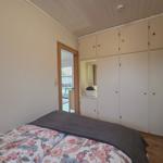 Schlafzimmer mit Bett, Schränken und Tür zum Balkon.