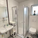 Badezimmer mit Dusche, Waschbecken und Toilette.