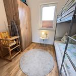 Zimmer mit Doppelstockbett, Kleiderschrank und Rundteppich.