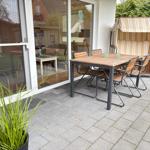 Terrasse mit Tisch, Stühlen und Strandkorb. Durchgang ins Haus mit Blick ins Wohnzimmer.