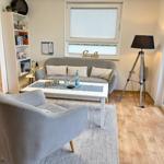 Wohnzimmer mit Sofa, Sessel, Tisch und Fenster.